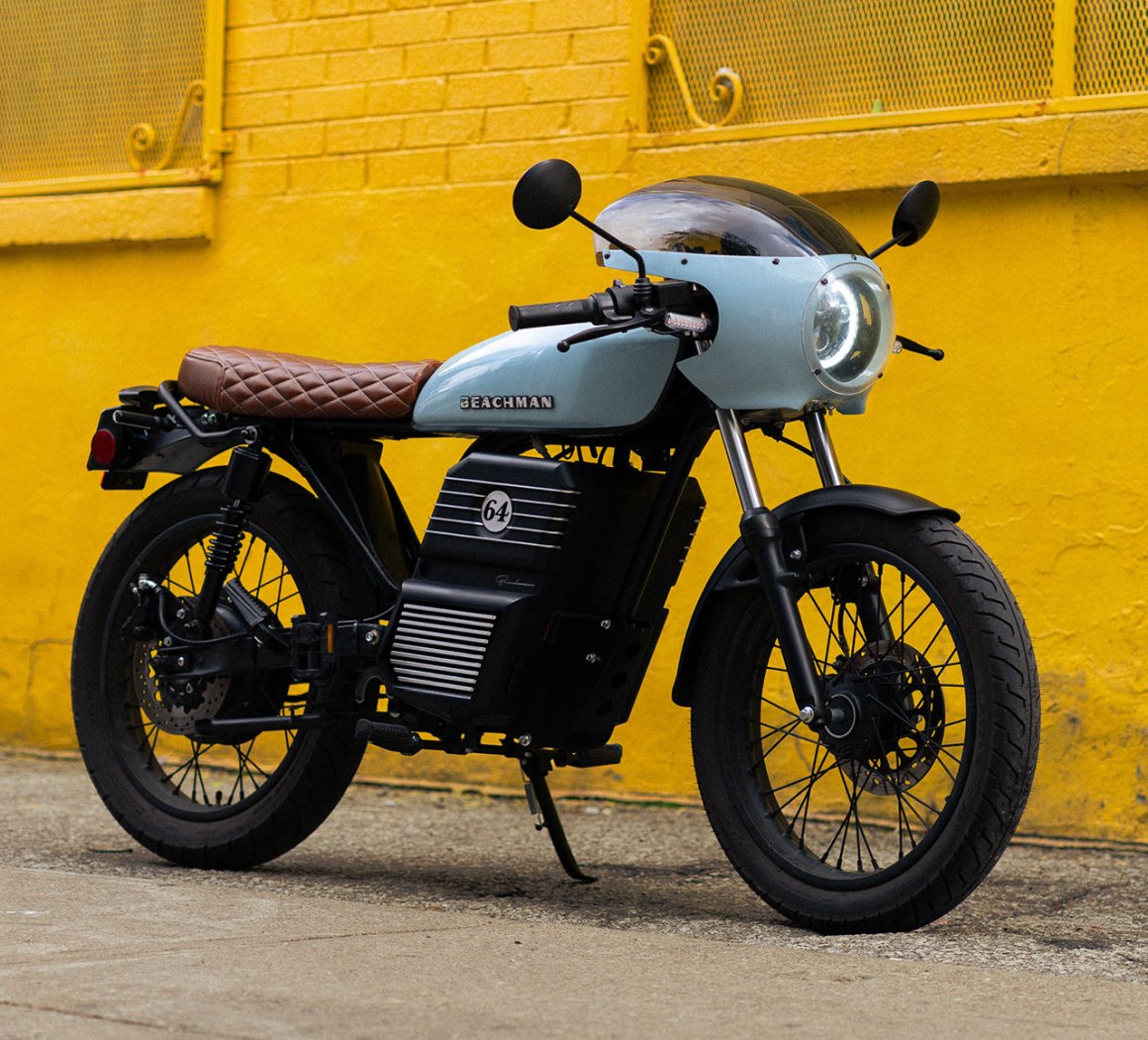 A stylish electric motorcycle with a retro design, featuring a light blue body, brown quilted seat, and set against a vibrant yellow wall.