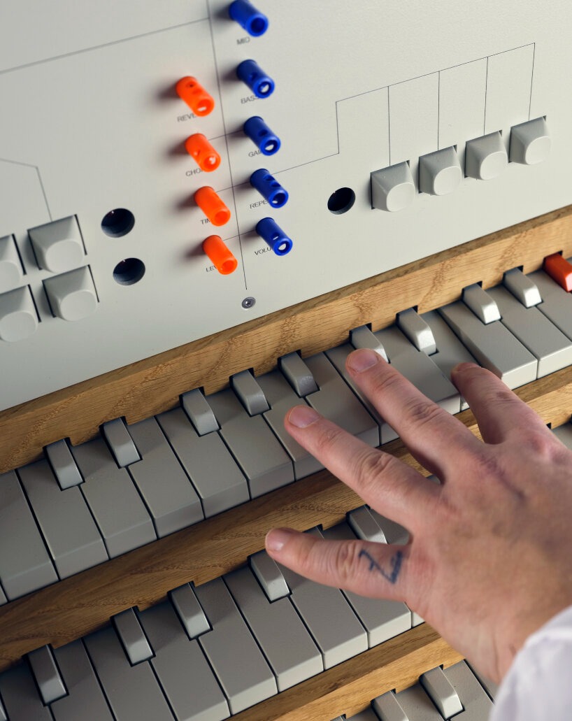 Close-up of a person's hand playing an electronic keyboard with various colorful controls above it.