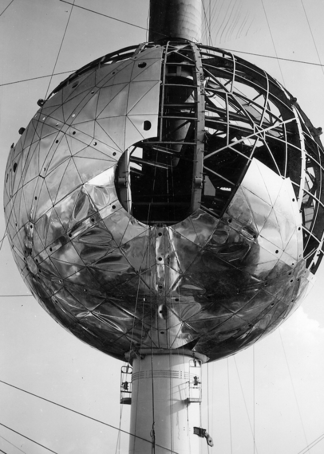 Close-up view of a partially constructed sphere of the Atomium in Brussels, showcasing its shiny metallic surface and structural framework.