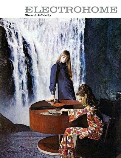 A retro advertisement for Electrohome showcasing two women, one standing and one seated at a stylish stereo console, with a dramatic waterfall in the background.