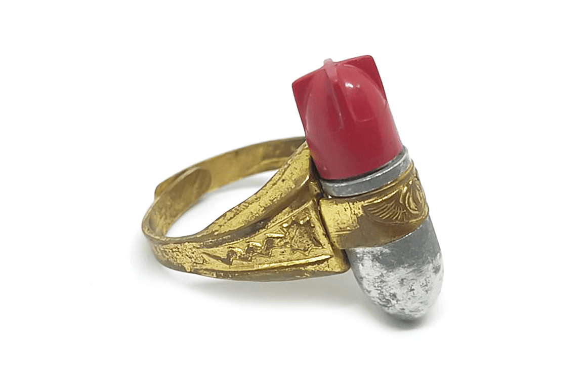 A vintage cereal toy ring designed to resemble a cartoonish bomb, featuring a red tip and a silver body with decorative golden accents.